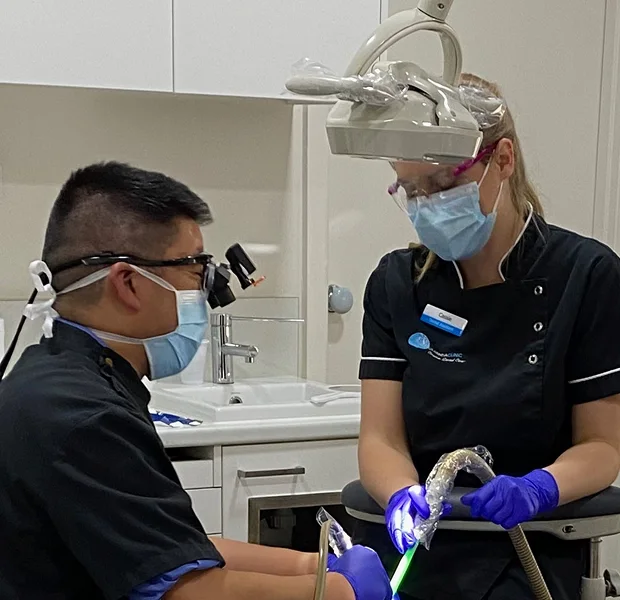 Dentist and assistant preparing patient in dental chair for procedure in a professional clinic.